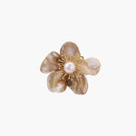 Flower-shaped brooch with iridescent shell petals, freshwater pearl center, and gold-plated radiating details.