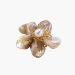 Flower-shaped brooch with iridescent shell petals, freshwater pearl center, and gold-plated radiating details.