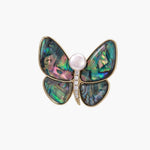 Gold-plated butterfly brooch with iridescent abalone shell wings and freshwater pearl accent on cream background.