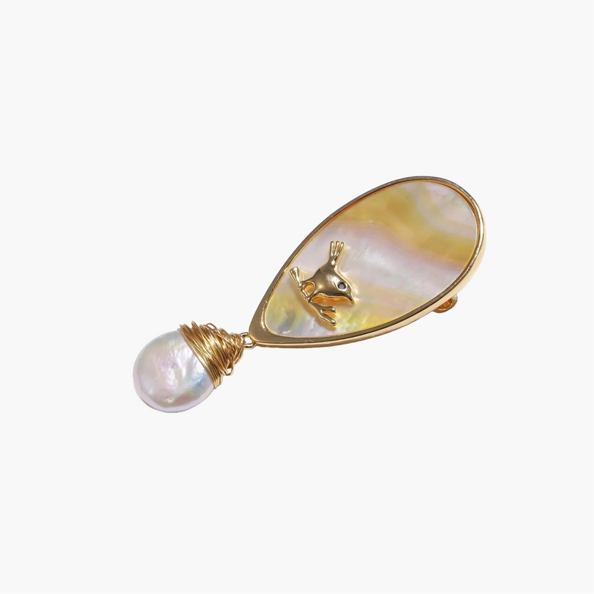 Iridescent shell brooch with gold bird accent and wire-wrapped baroque pearl drop on cream background.