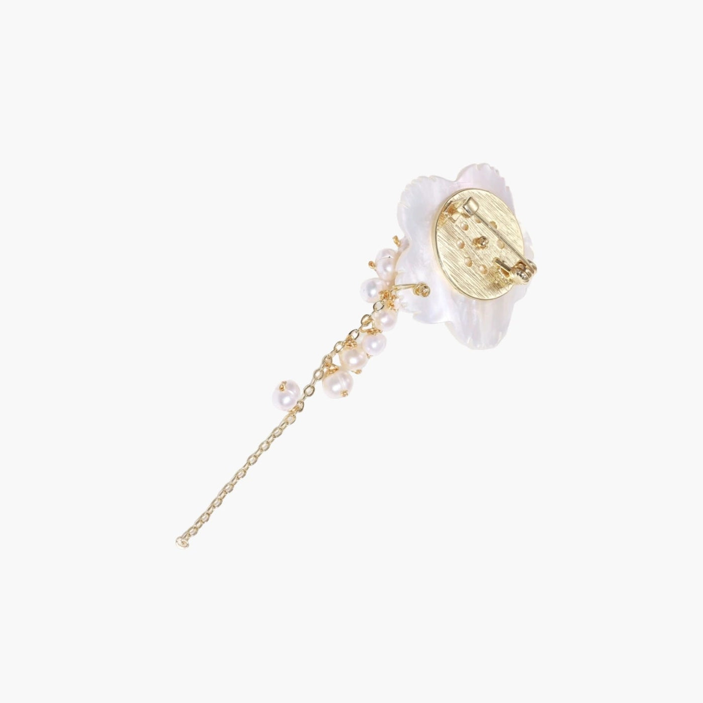 Iridescent shell flower brooch with carved petals and cascading freshwater pearls on gold chain against cream background.