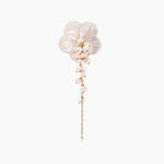 Iridescent shell flower brooch with carved petals and cascading freshwater pearls on gold chain against cream background.
