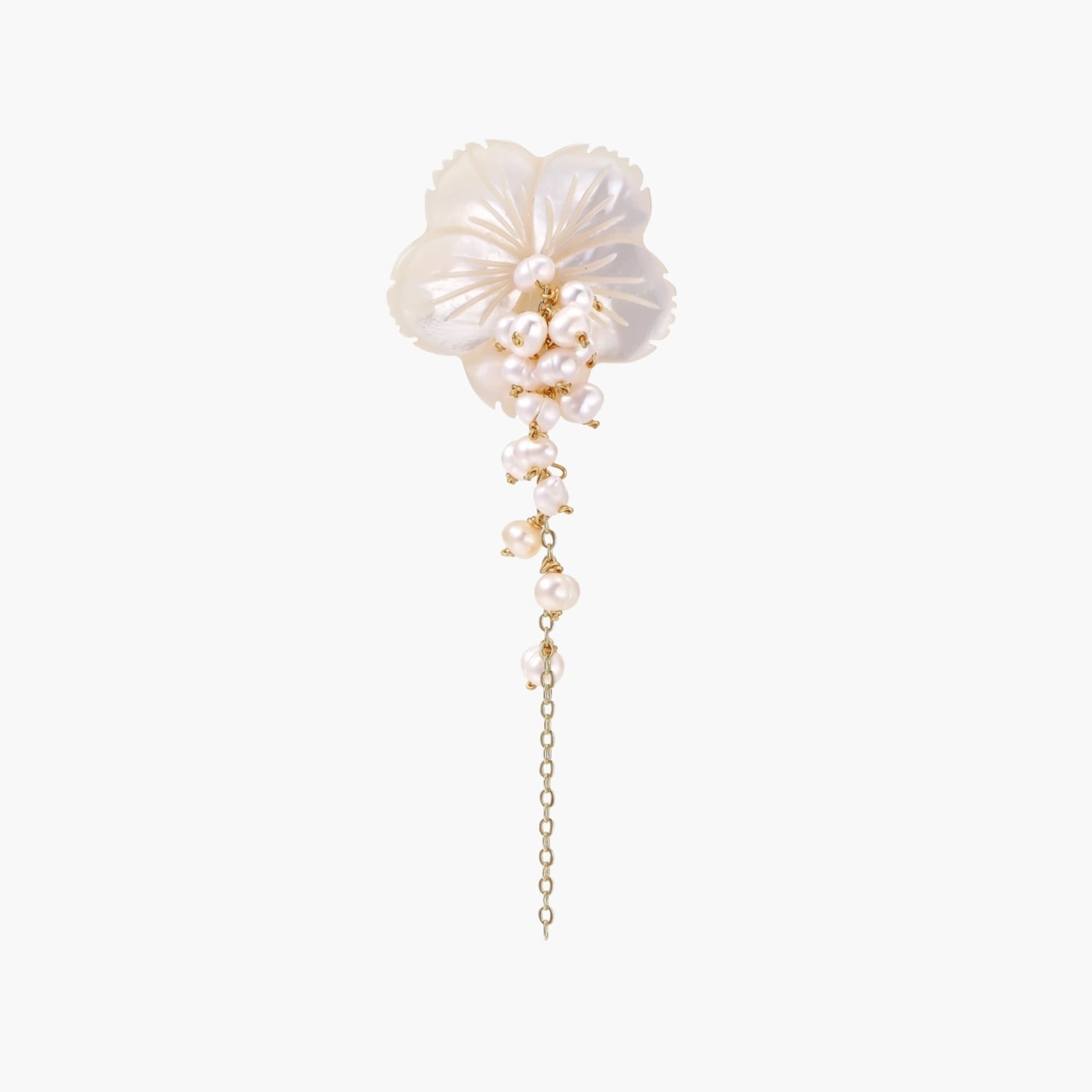 Iridescent shell flower brooch with carved petals and cascading freshwater pearls on gold chain against cream background.