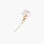 Iridescent shell flower brooch with carved petals and cascading freshwater pearls on gold chain against cream background.